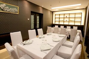 A conference room with a long table set for a meeting, surrounded by chairs, and a wall with a lighted display. - Cajupi (Gjirokastër)