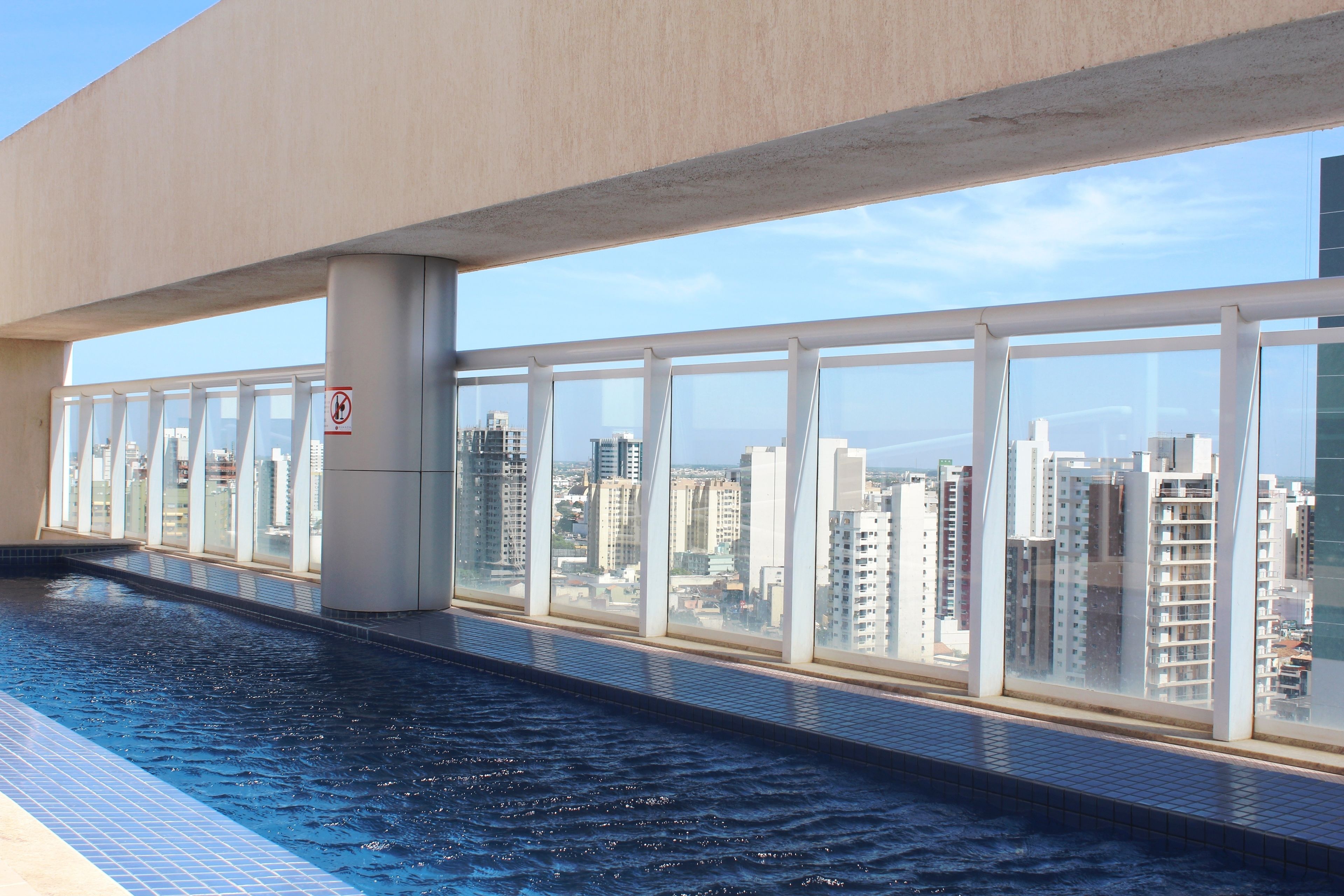 A swimming pool with a city view, large windows, and a no swimming sign.
