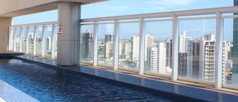 Piscina con vista a la ciudad, ventanas amplias y un cartel de prohibición de baño.