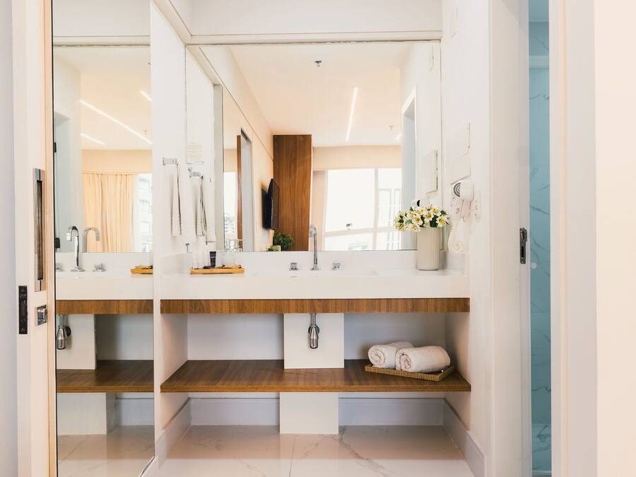Une salle de bain moderne avec deux vasques, des étagères en bois, un miroir et un porte-serviettes.