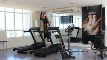 Een sportschool met loopbanden, een hometrainer en een vastzetfiets.
