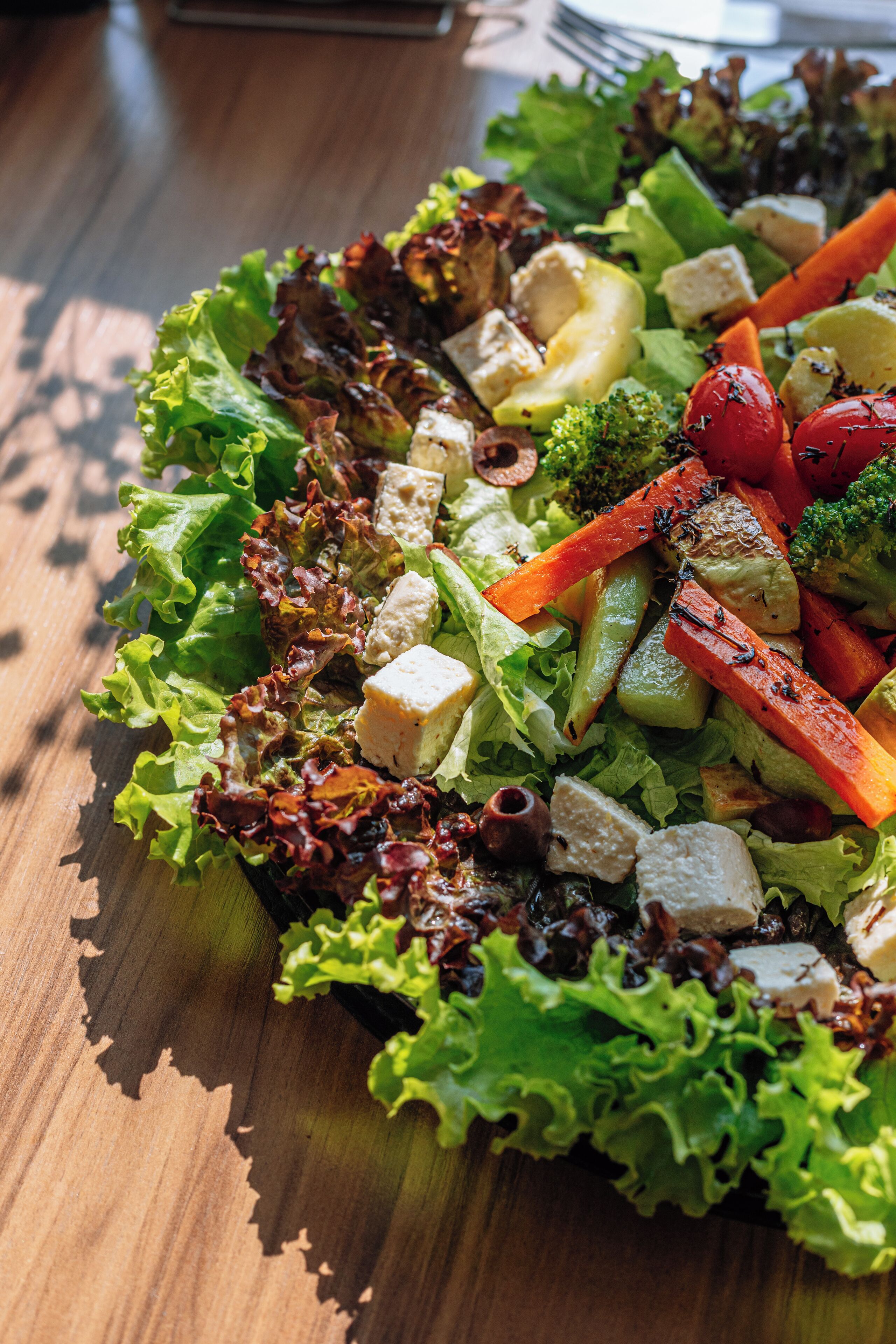 A wooden table with a salad.