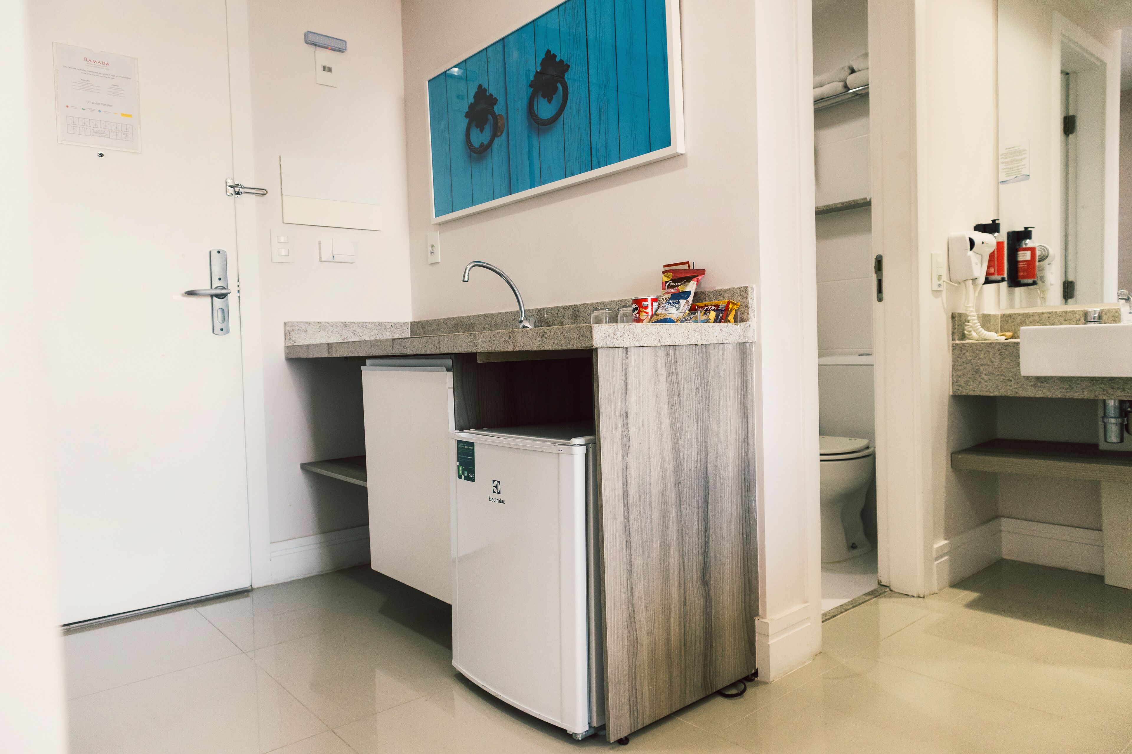 Eine kompakte Küche mit integriertem Kühlschrank, Spüle und einer Arbeitsplatte mit Toilettenartikeln.