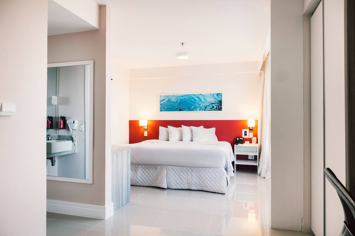 Una habitación de hotel moderna con una cama grande, una mesita de noche y un espejo.