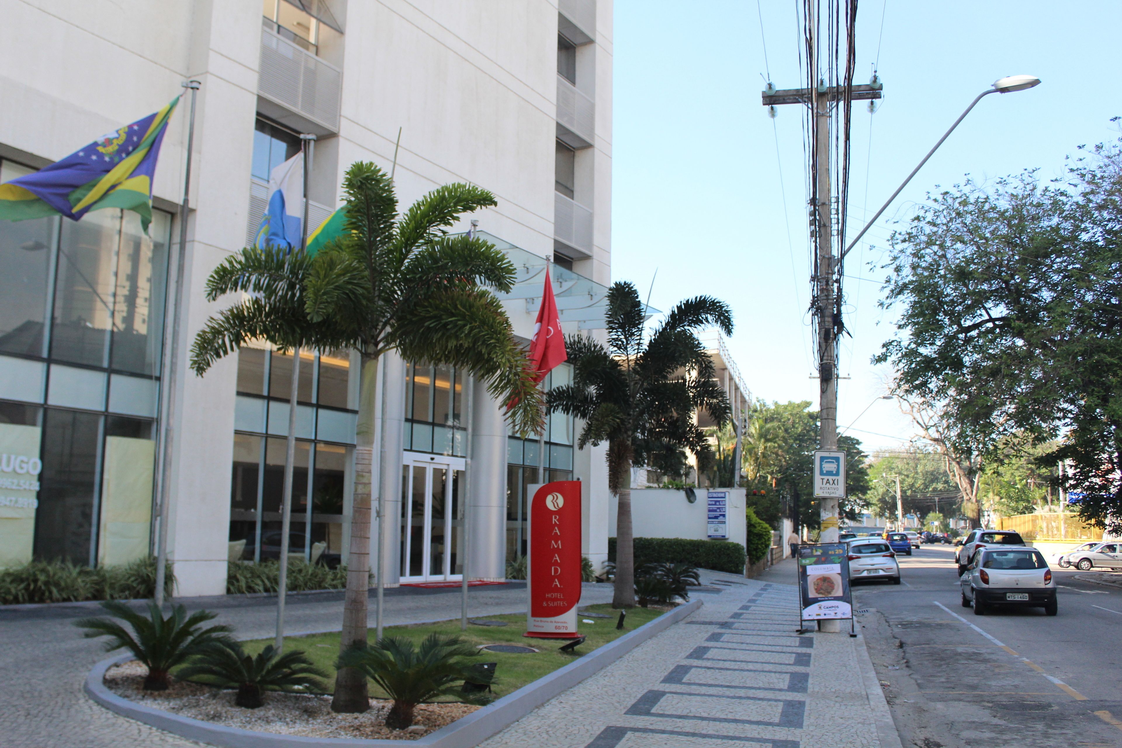 Un hotel con fachada moderna, palmeras y banderas.