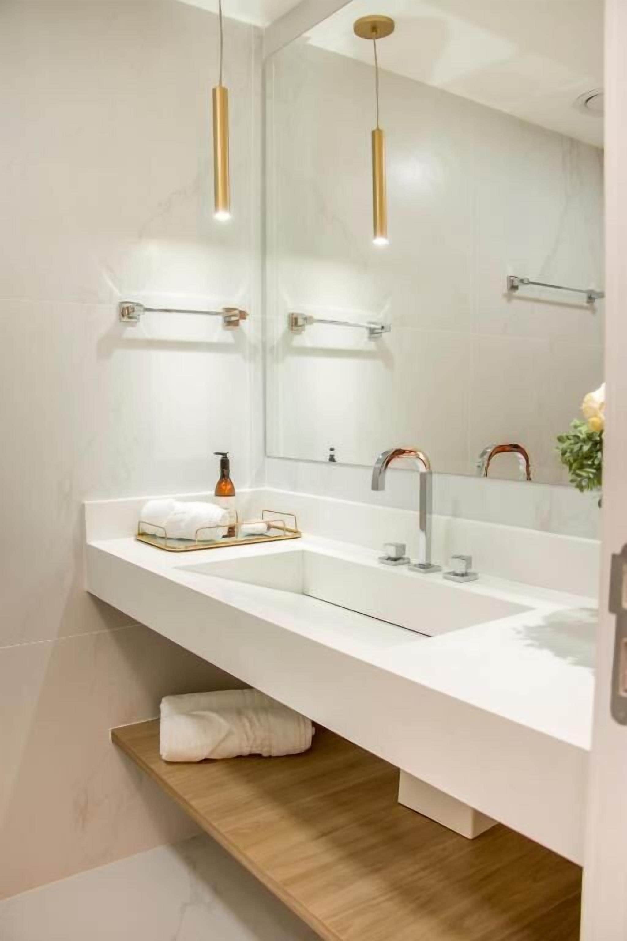 A modern bathroom with a white vanity, two sinks, a large mirror, and pendant lights.