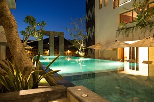 Una piscina al aire libre, sombrillas, sillones reclinables de piscina