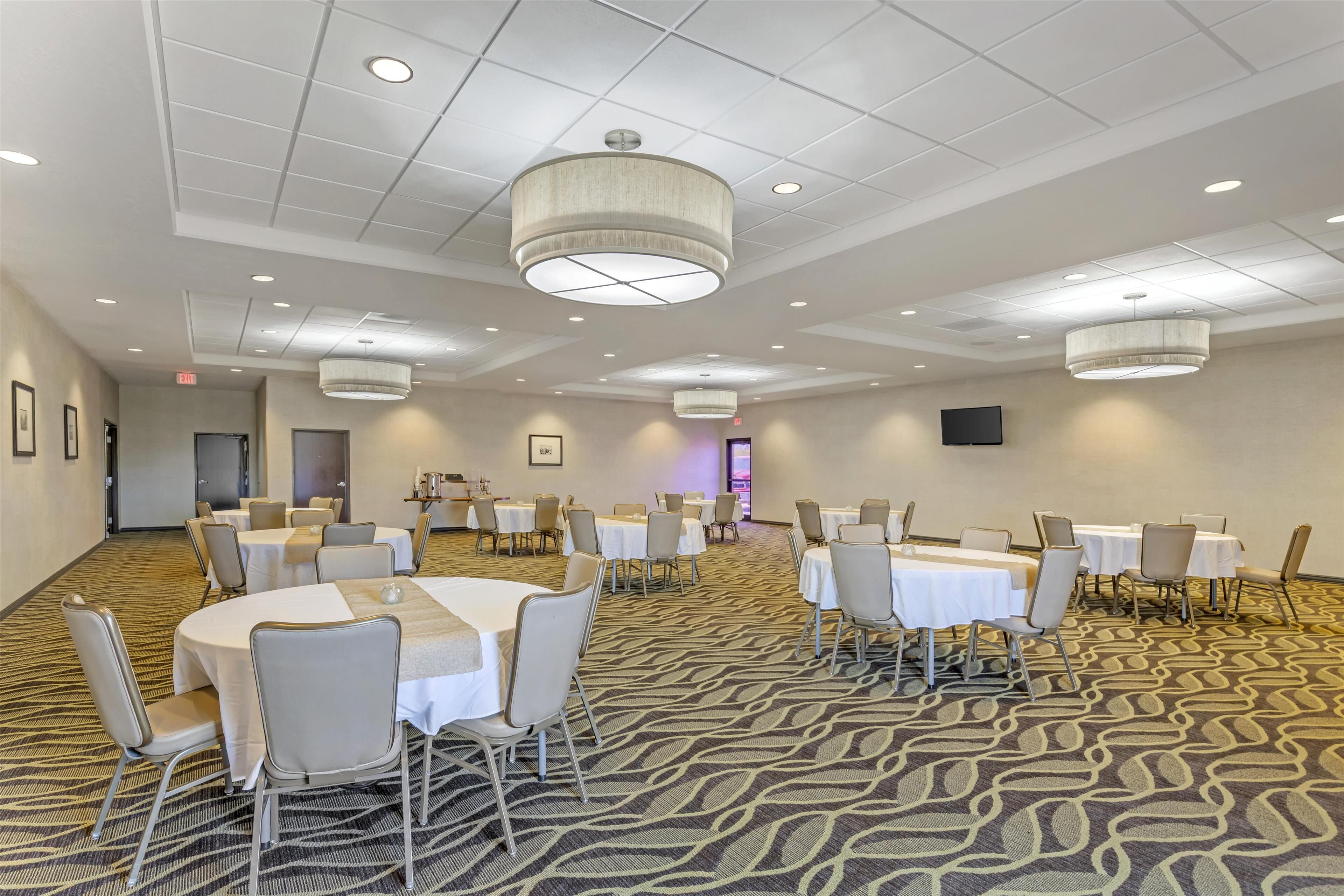 A conference room with round tables, chairs, and a patterned carpet.