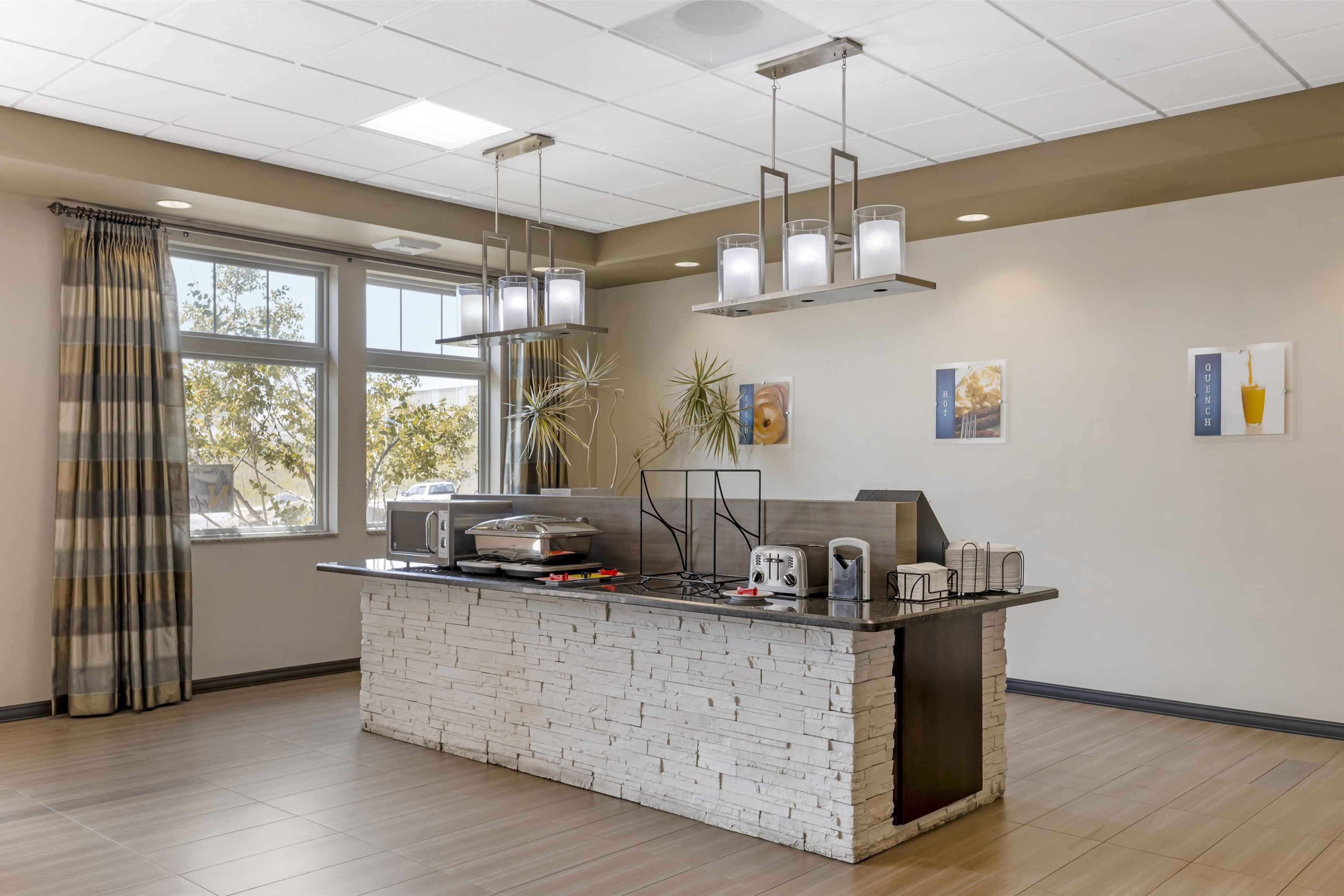 Una cocina moderna con una isla de ladrillo, luces colgantes y vistas al exterior.