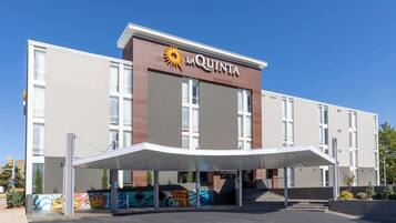 A hotel named La Quinta with a modern design, featuring a covered entrance and a mural on the side.