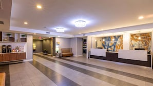 A spacious lobby with a reception desk, seating area, and a staircase leading to upper floors.