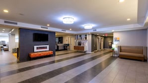A spacious lobby with a modern design, featuring a seating area, a television, and a reception desk.