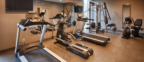 Une salle de sport équipée de tapis de course, de vélos elliptiques et de matériel de musculation.