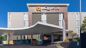 A hotel entrance with a covered walkway, a prominent sun logo, and a mural on the wall.