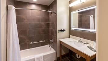 Un baño moderno con una bañera, una ducha con puerta de vidrio, un lavamanos con espejo y un perchero para toallas.