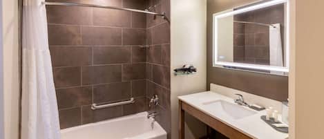 Un baño moderno con una bañera, una ducha con puerta de vidrio, un lavamanos con espejo y un perchero para toallas.