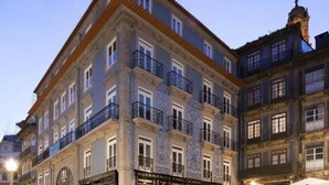 A multi-story building with a classic architectural style, featuring a central courtyard with outdoor seating and a few people. - Porto A.S. 1829 Hotel (Porto)