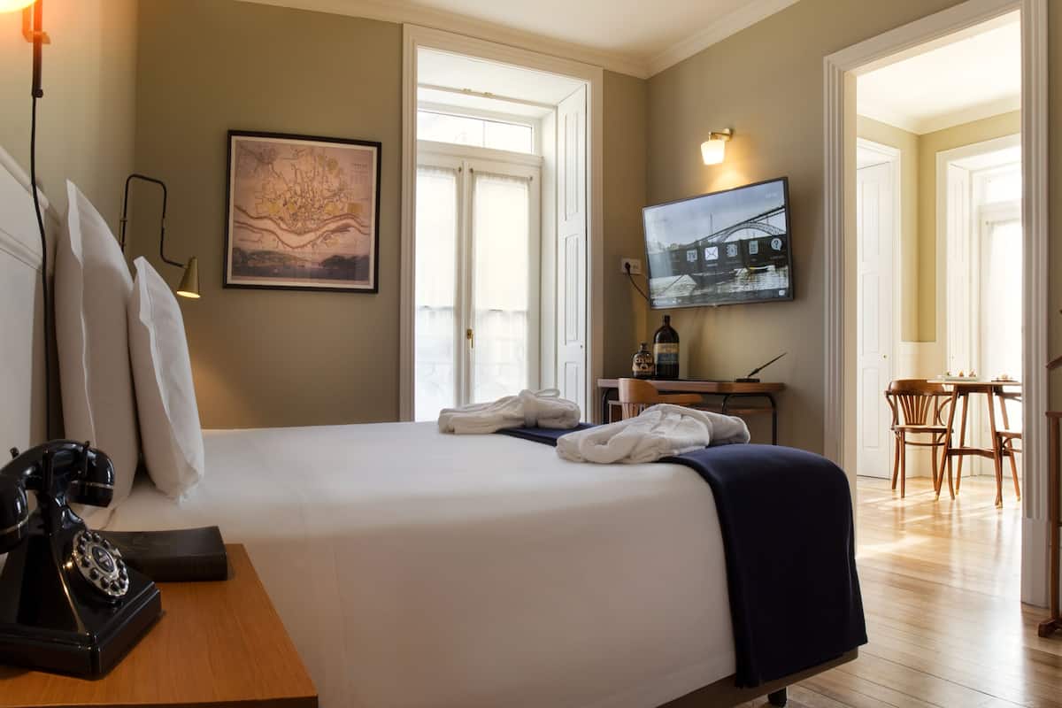 A hotel room with a bed, a desk, a television, a map, and a coat rack.