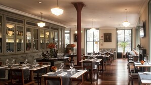 A spacious restaurant with multiple dining tables, wooden chairs, and a large window offering a view of the city. - Porto A.S. 1829 Hotel (Porto)