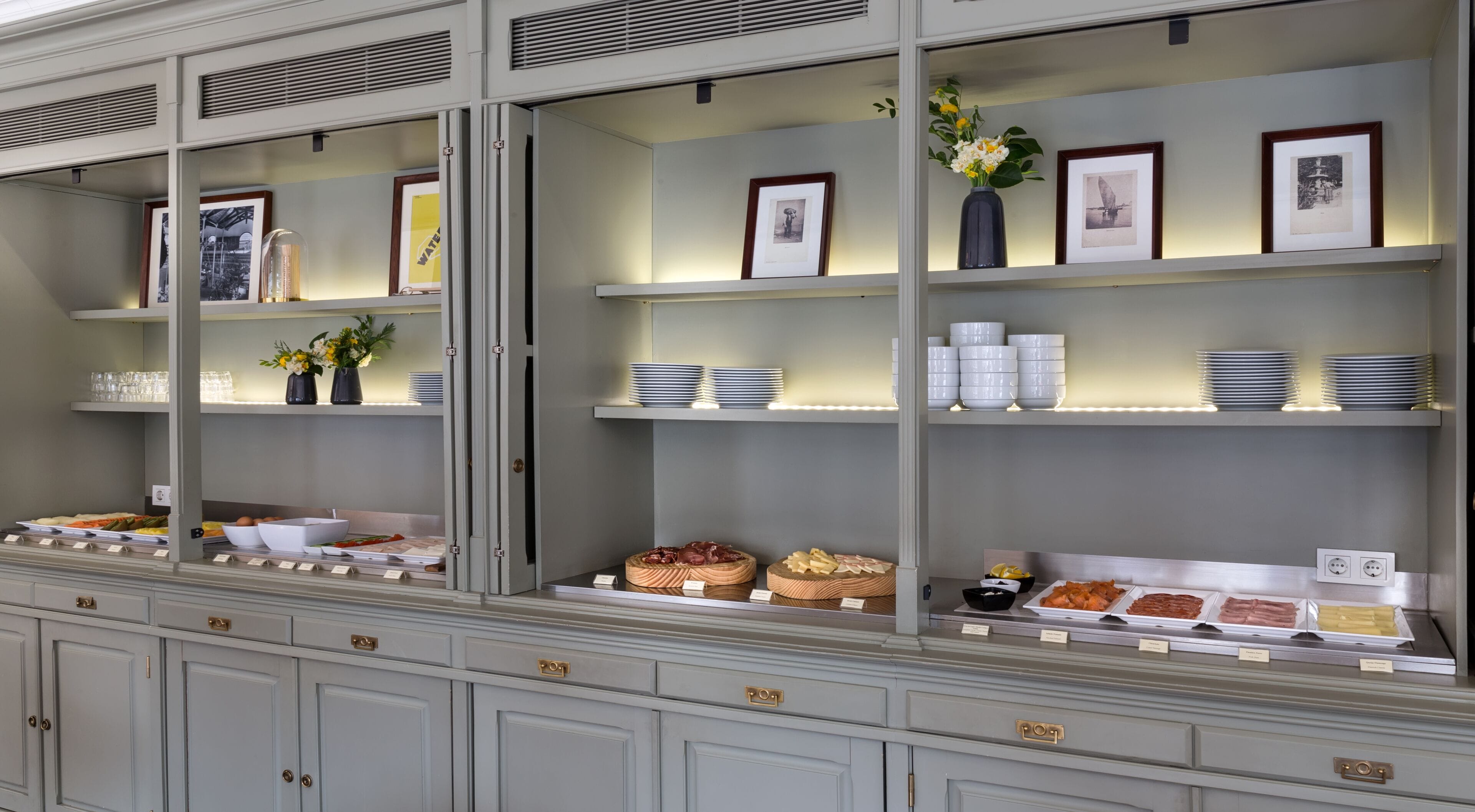 Un espace buffet proposant une variété de plats, de verrerie et des tableaux encadrés disposés sur des étagères.