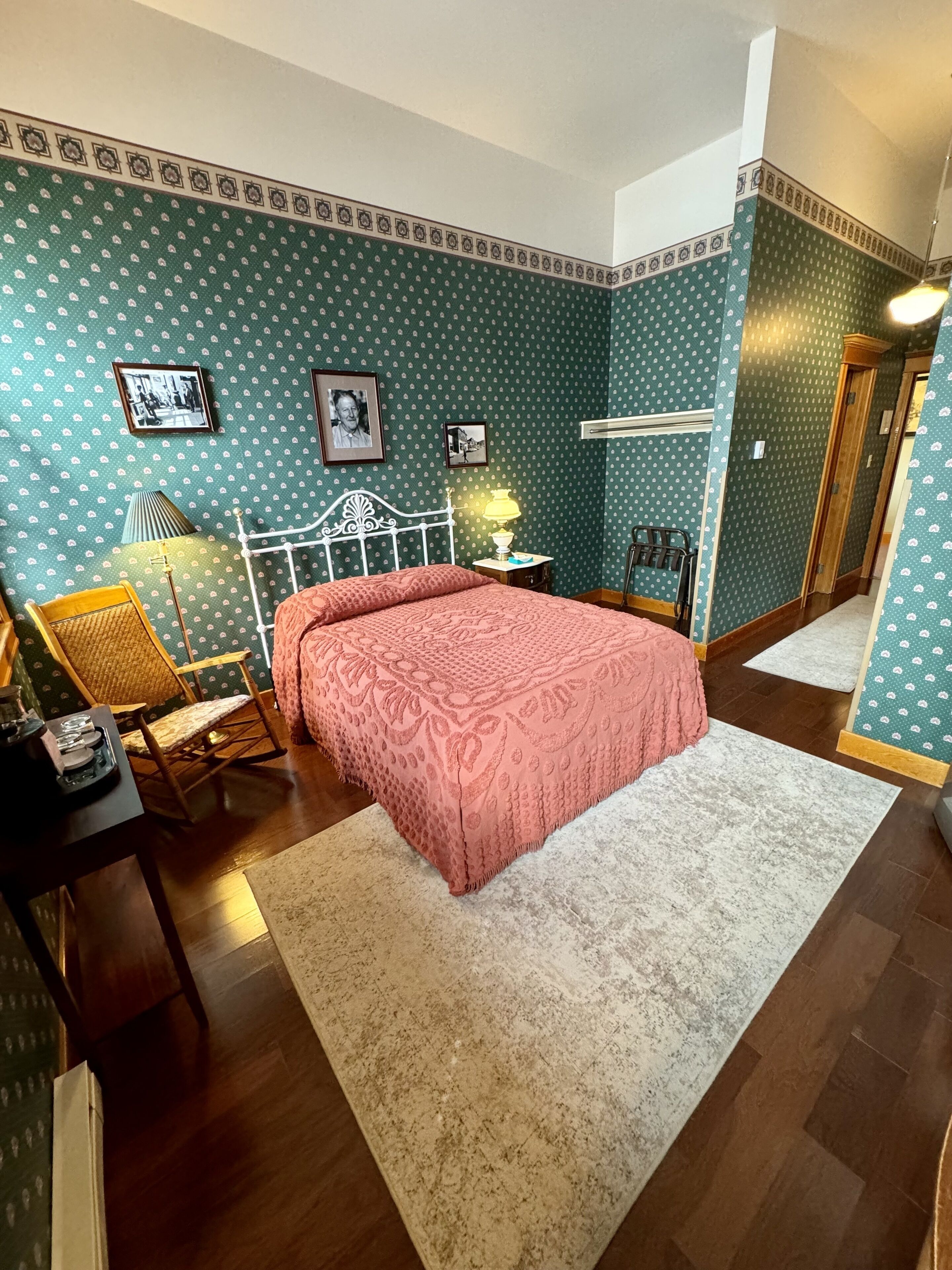 A bedroom with a bed, a chair, a nightstand, and a lamp.