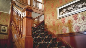 Una escalera con barandillas de madera y alfombra estampada con motivos florales.