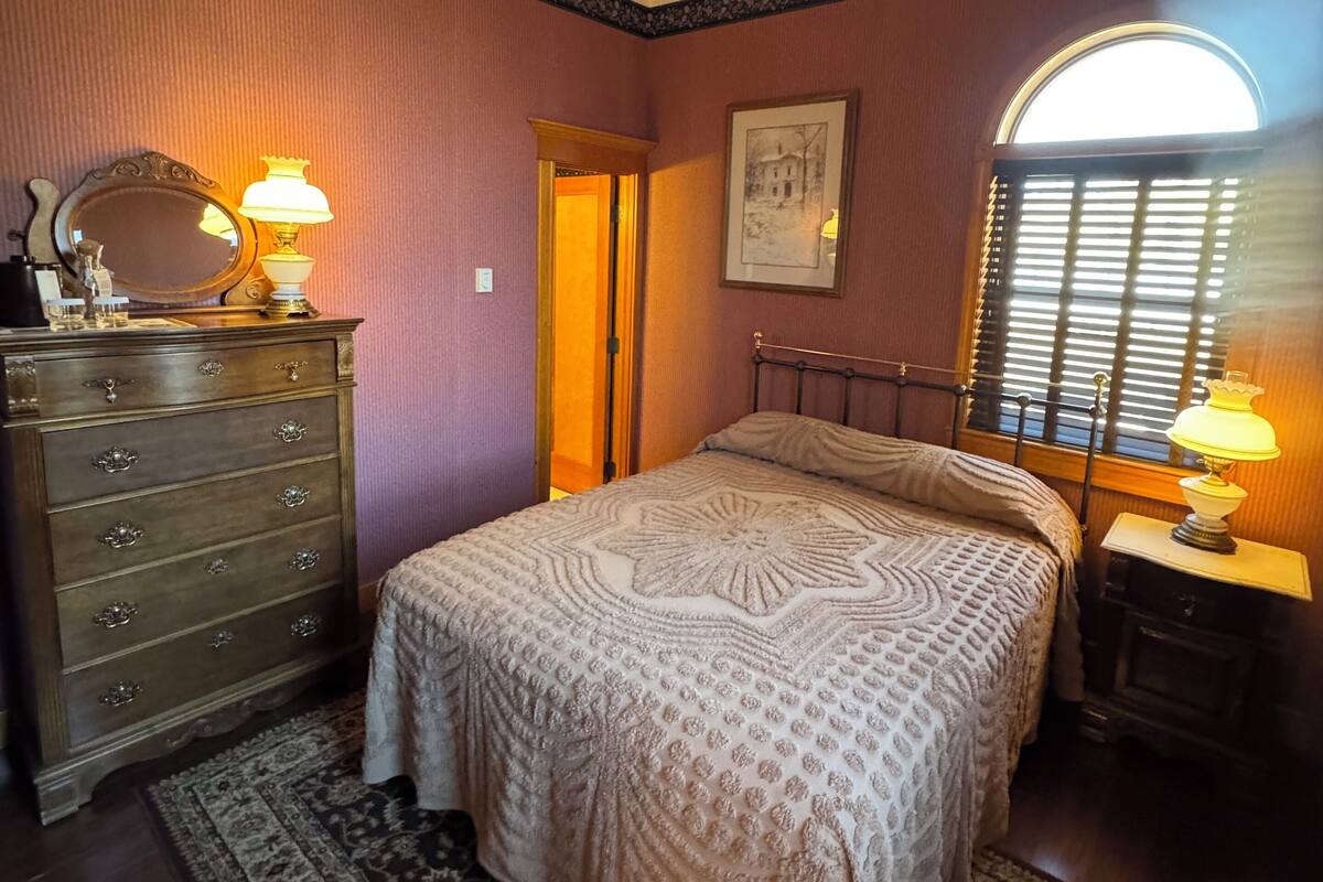 A bedroom with a bed, dresser, and two lamps.