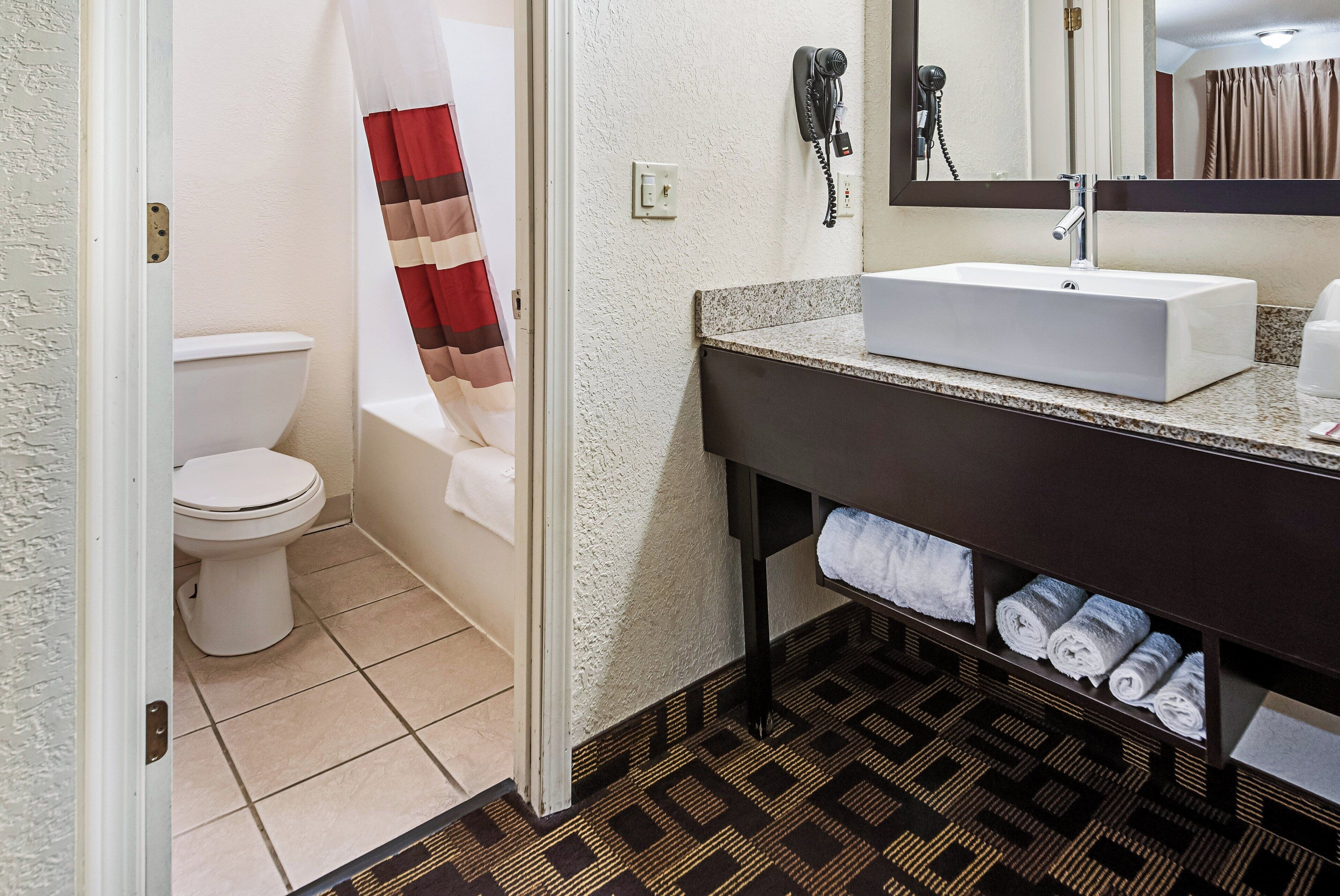 Une salle de bain avec un lavabo blanc, un porte-serviettes avec des serviettes, des toilettes et un rideau de douche.