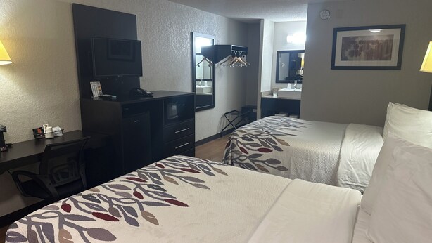 A hotel room with two beds, a desk with a computer, a TV, and a mirror. - Red Roof Inn Anderson, IN (Anderson)