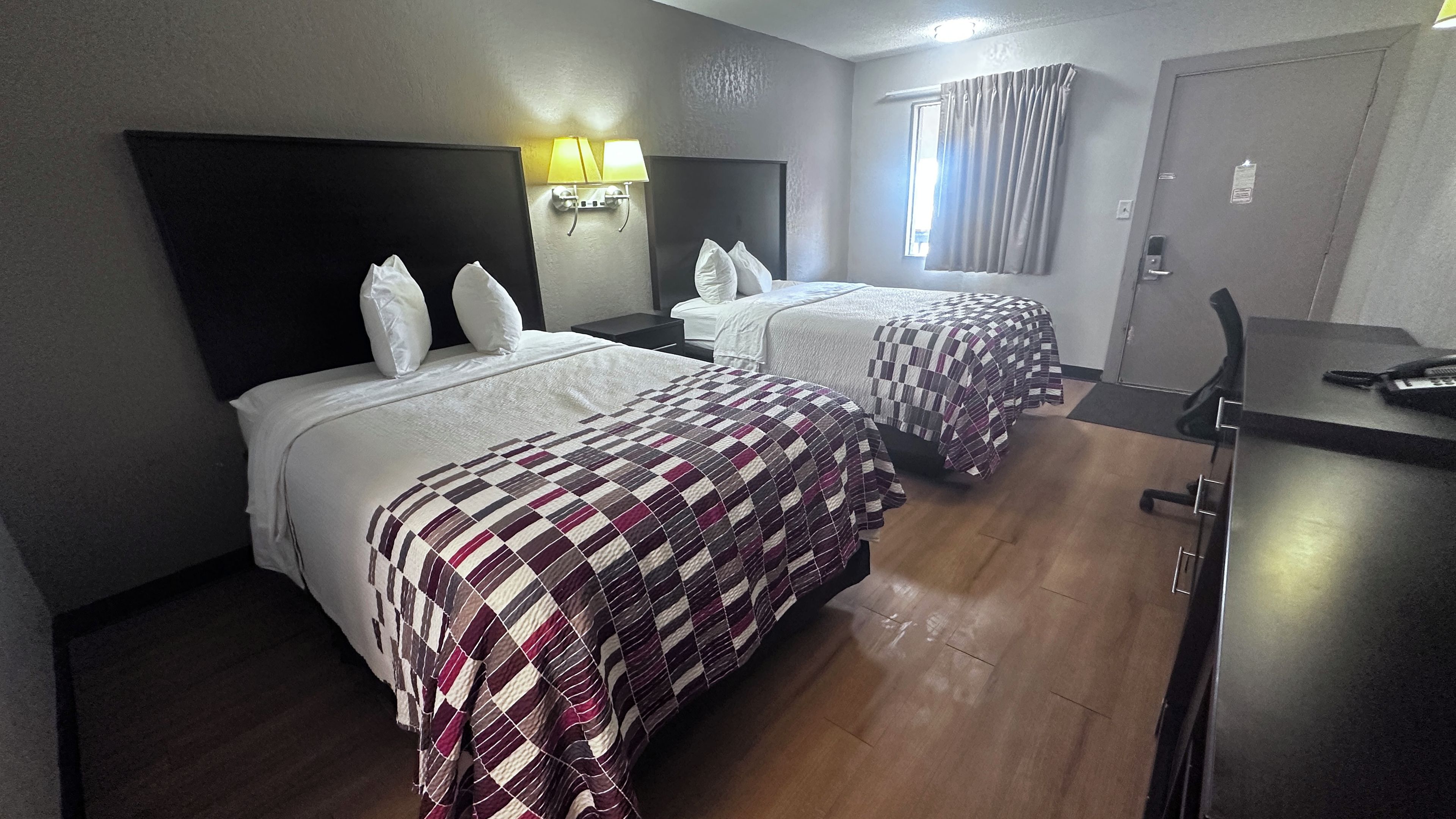 Habitación de hotel con dos camas, un escritorio y una silla.