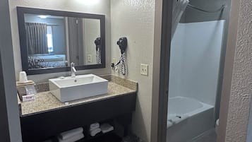 A bathroom with a sink, mirror, and shower.