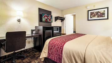 Ein Hotelzimmer mit Bett, Schreibtisch, Stuhl, Fernseher und Mikrowelle.