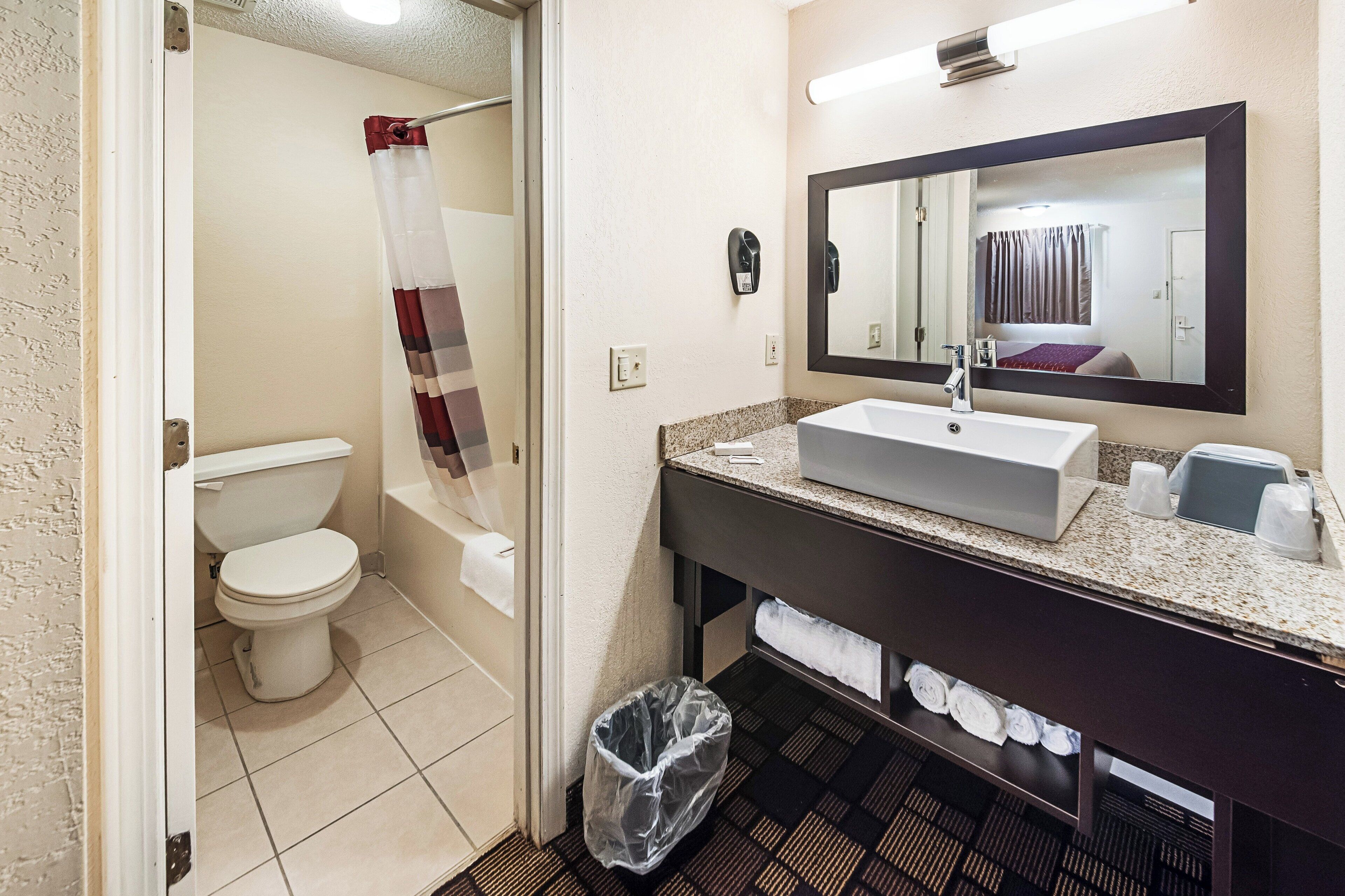 A bathroom with a toilet, a sink, a mirror, and a shower curtain.