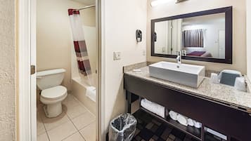 A bathroom with a toilet, a sink, a mirror, and a shower curtain.
