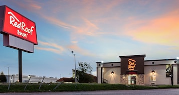 A Red Roof Inn with a prominent red sign and a neon sign on the building.