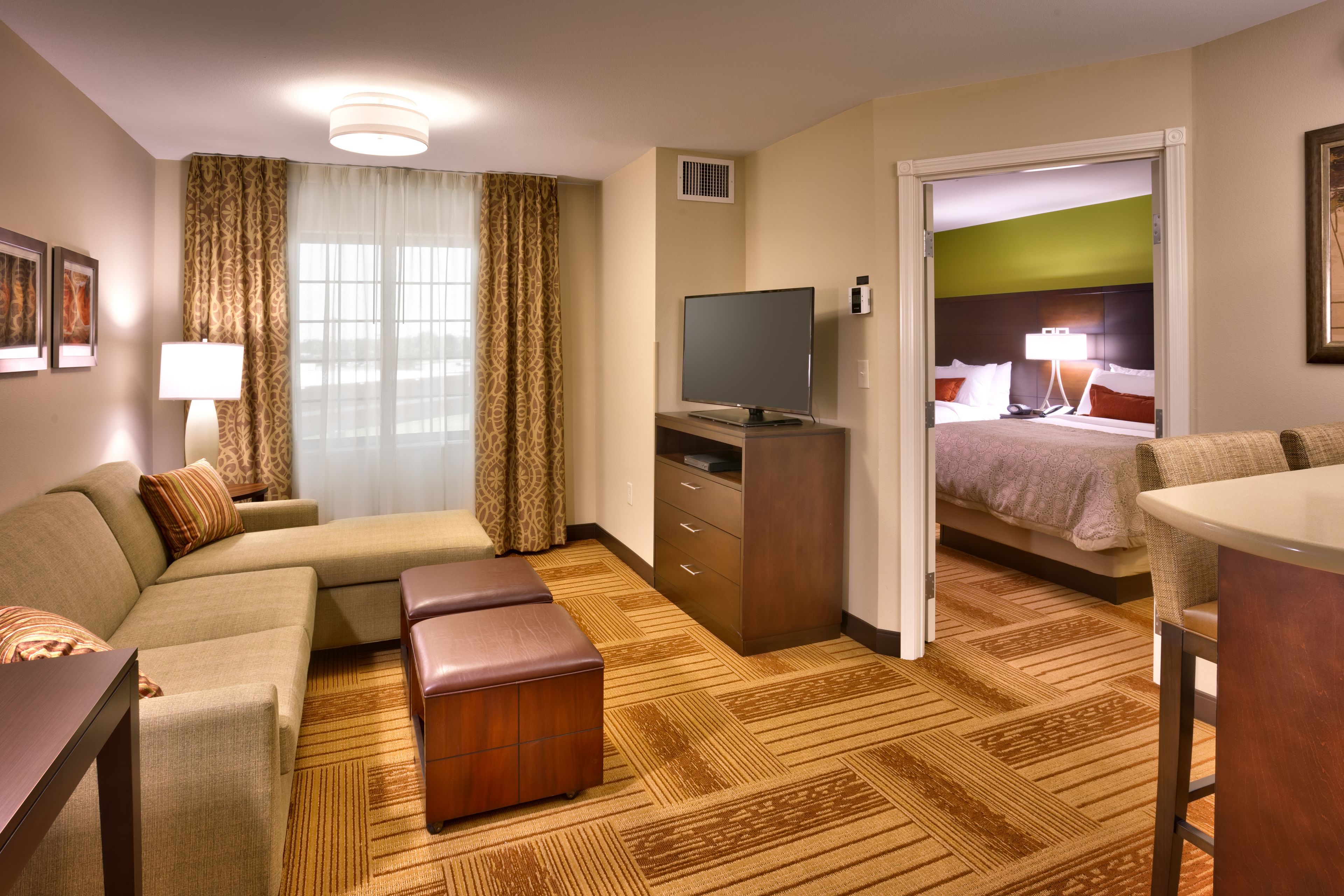 A hotel room with a sofa, a TV, a desk, a chair, and a bed.
