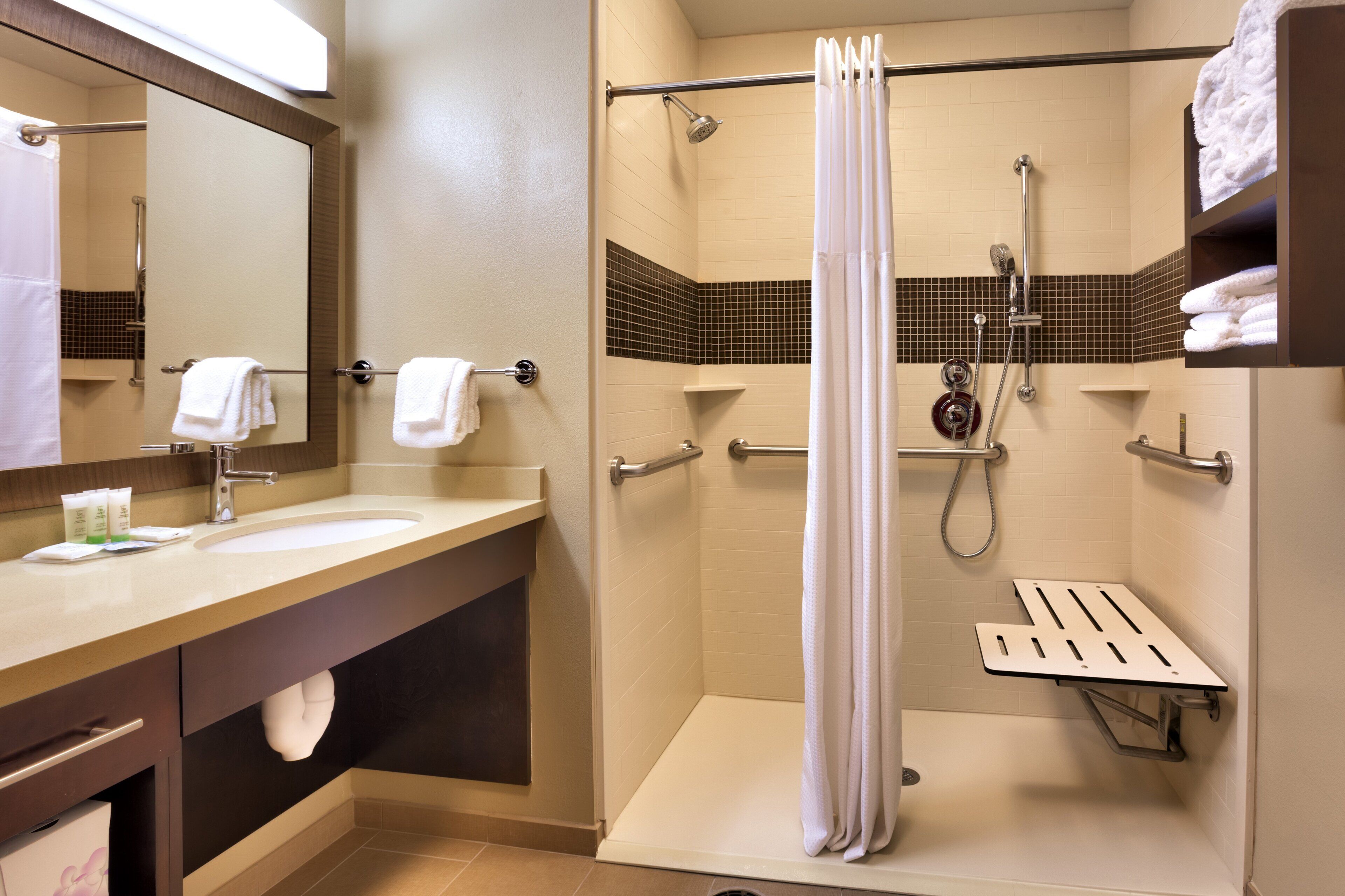 Une salle de bain d’hôtel équipée d’une douche, d’un lavabo et d’un miroir.