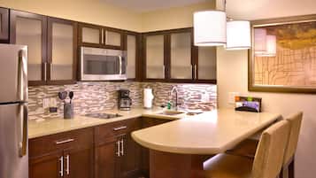 Una cocina compacta con microondas, refrigerador y cafetera.