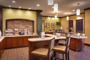 Un espace pour le petit-déjeuner à l’hôtel, avec un mur en pierre, des meubles en bois et un buffet.