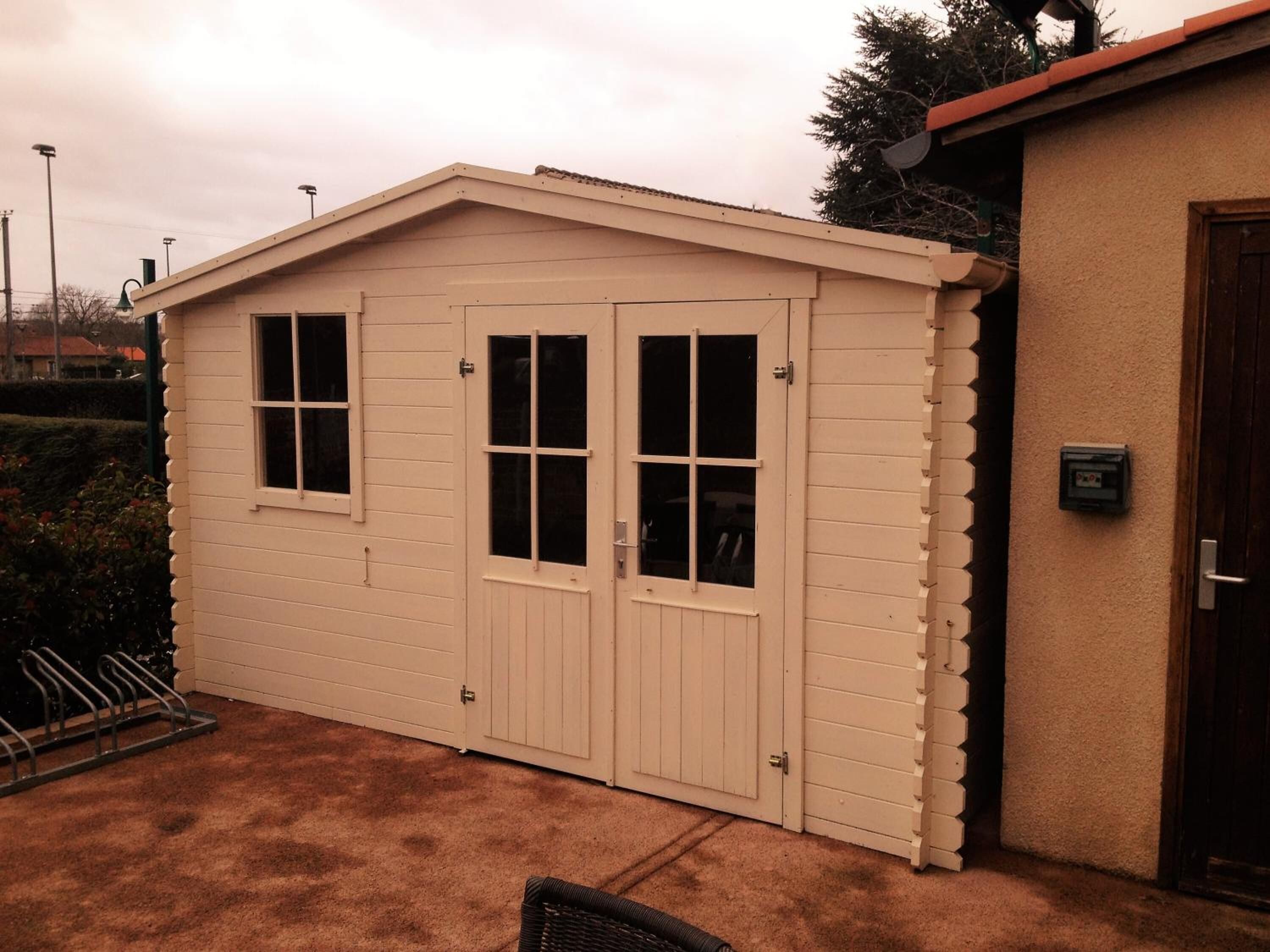 A small, single-story shed with a gabled roof and two sets of double doors.