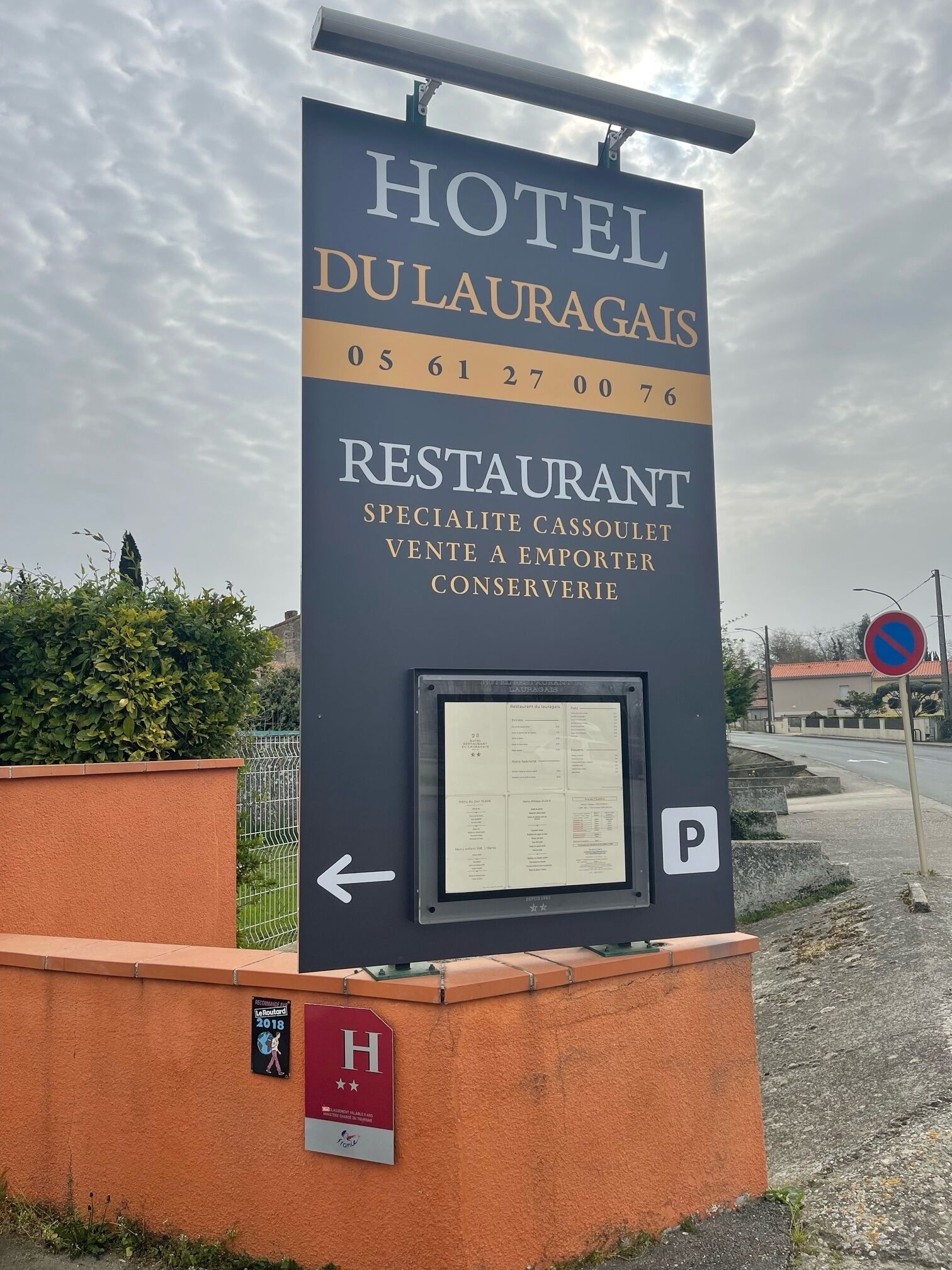 Une enseigne indiquant l’hôtel Dulauragas, avec des informations sur le restaurant et le parking.