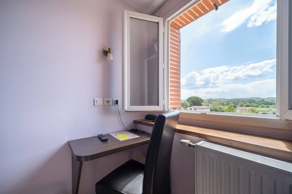 Una habitación con escritorio, silla y ventana con vistas al paisaje.
