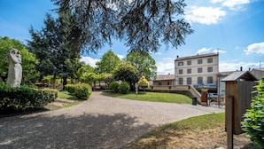 A paved driveway leading to a building with a sign indicating it is a hotel and restaurant. - Hotel du Lauragais (Villefranche-de-Lauragais)
