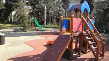 A playground with a slide, climbing structure, and a green slide.