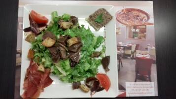 A plate of food with a salad, meat, and vegetables.
