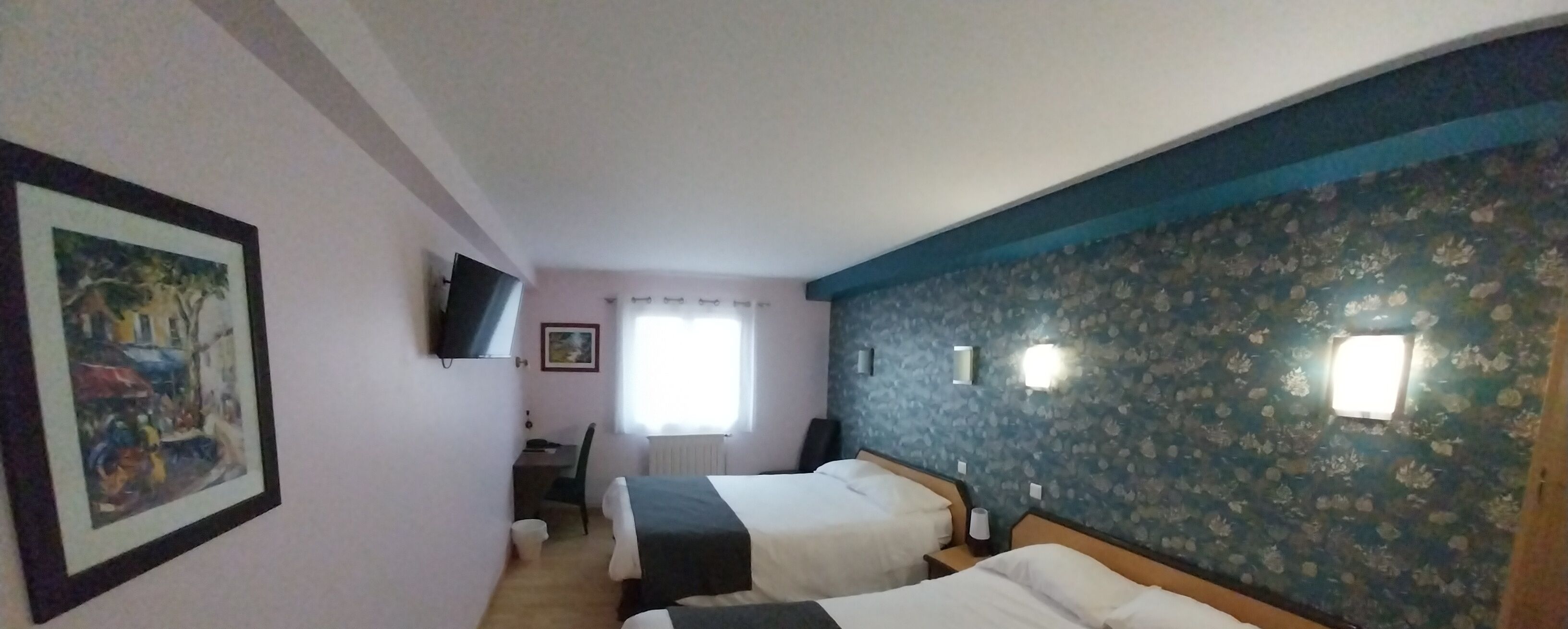 A hotel room with two beds, a desk, a chair, a TV, and a window with curtains.