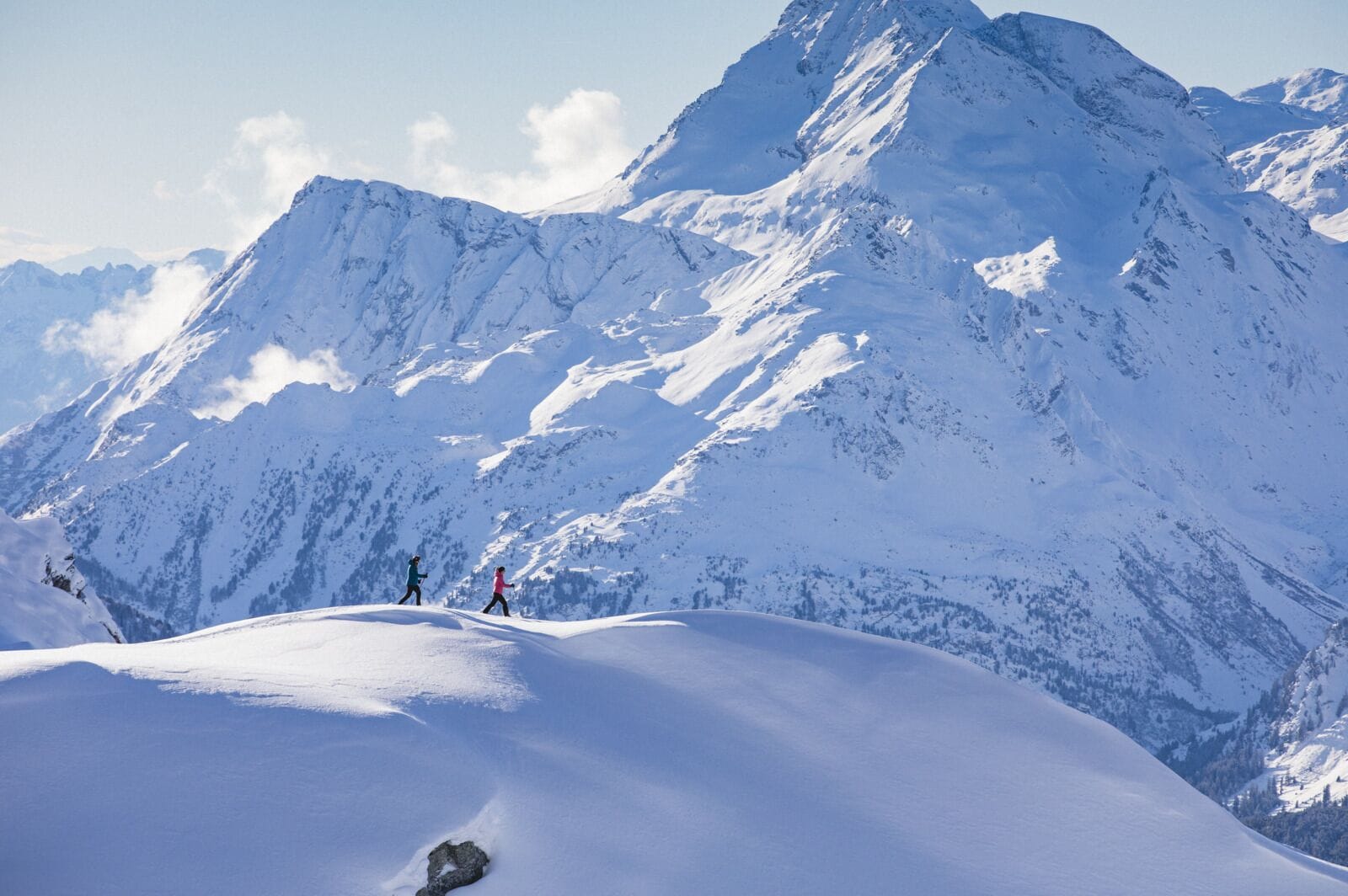 A snow-covered mountain with three people hiking.