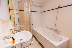 A modern bathroom with a glass-enclosed shower, a white sink, and a bathtub.