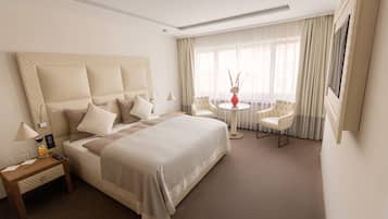 A hotel room with a large bed, a bedside table with a lamp, a small round table with chairs, and a large window with curtains.