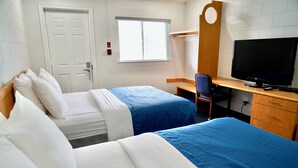 Une chambre d’hôtel avec deux lits, un bureau avec une télévision, une chaise et une armoire.